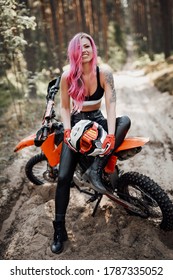 Happy Young Woman With Pink Hair And Tattoo On Hand Sitting On Her Modern Motocross Bike In Woods