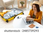 Happy young woman planning vacation travel with laptop pc, reading tourist blog online, booking tickets or hotel room on web, getting ready for abroad journey at home, free space