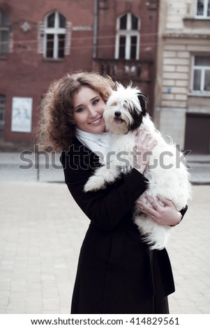 Happy young woman playing with dog  in the city