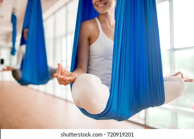 Happy young woman practicing aero yoga in blue hammock