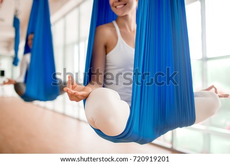Happy young woman practicing aero yoga in blue hammock