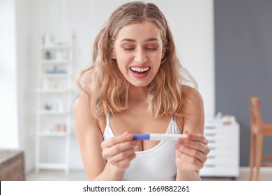 Happy Young Woman With Pregnancy Test In Bathroom