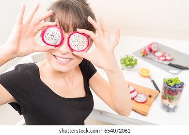 Happy Young Woman Puts Slices Of Dragon Fruit As Glasses. Healthy Eating - Concept.