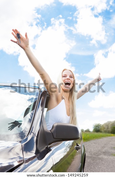 Happy Young
Woman Raising Hand Out Of Car
Window
