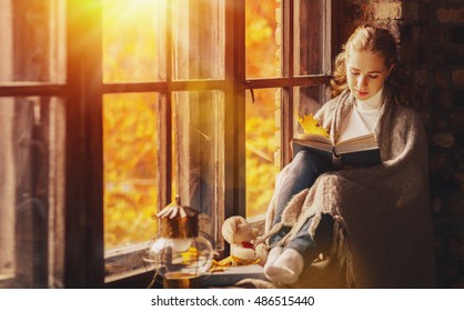 Happy Young Woman Reading A Book By The Window In The Fall