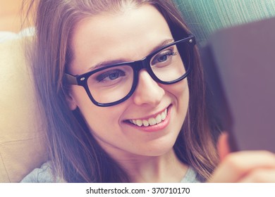 Happy young woman reading an e-book on her couch at home - Shutterstock ID 370710170
