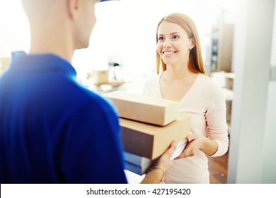 Happy Young Woman Receiving A Box From Mailman