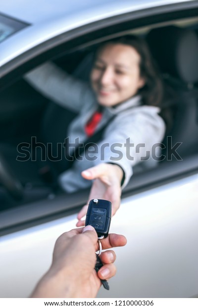 Happy young woman receiving the keys of her new\
car. Buy or rent a car\
concept.