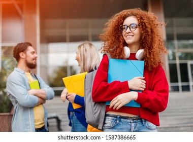 Happy Young Woman With Red Curly Hair Smiling And Looking Away While Standing On Street During College Admission Campaign