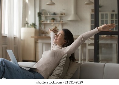 Happy young woman relaxing alone on cozy sofa put wireless computer on laps, raising her arms, female smiling with eyes closed enjoy carefree untroubled weekend, accomplish online task feeling free - Shutterstock ID 2133149029