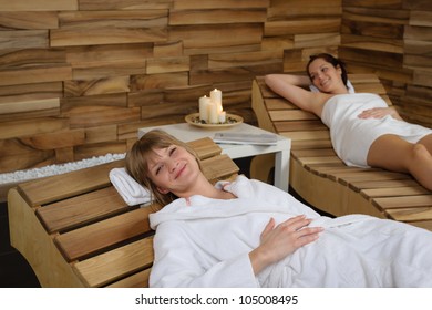 Happy Young Woman Relaxing On Wooden Chair At Wellness Center