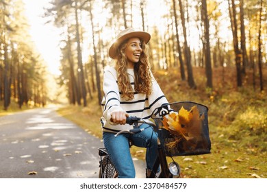 Happy young woman riding a bike, having fun in the autumn park. Concept of relaxation, nature. Active lifestyle. - Powered by Shutterstock