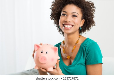 Happy Young Woman Saves Money In Piggy Bank