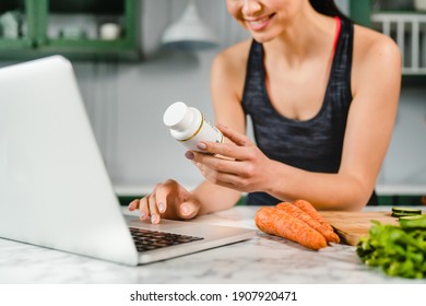 Happy Young Woman Searching Info In Laptop About Food Supplements In The Kitchen