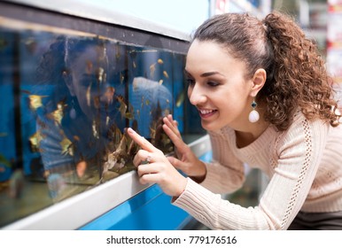 Happy Young Woman Selecting Aquarium Fish In Pet Shop