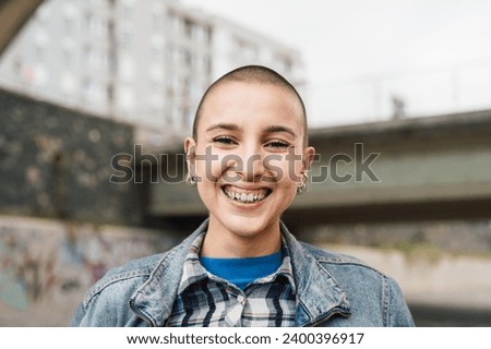 Happy young woman with shaved head smiling in front of camera 