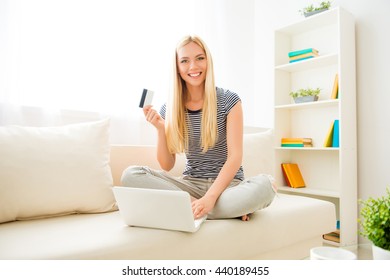 Happy young woman showing credit card and doing internet shopping
