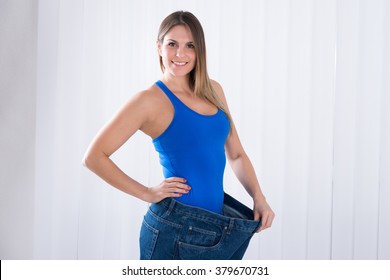 Happy Young Woman Showing Her Weightloss By Wearing Old Jeans