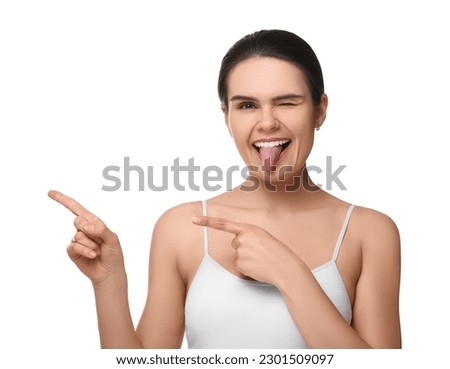 Happy young woman showing her tongue and pointing on white background