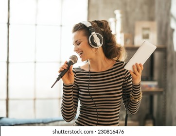 Happy Young Woman Singing Karaoke In Loft Apartment