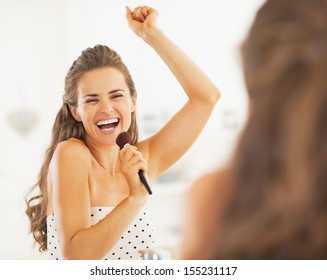 Happy Young Woman Singing In Makeup Brush In Bathroom