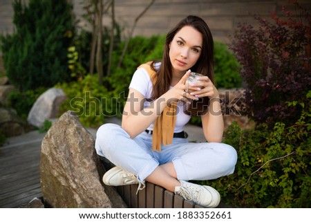 happy young woman sitting in a beautiful park and drinking spicy latte