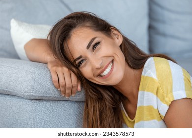 Happy young woman sitting on sofa at home Portrait of beautiful woman smiling and relaxing during summer. - Powered by Shutterstock