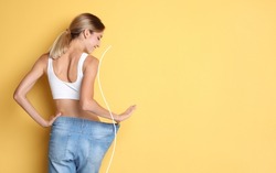 Fröhliche Junge Frau Mit Schlankem Körper In übergroßen Jeans Auf Gelbem Hintergrund, Platz Für Text. Gewichtsverlust