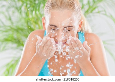 Happy young woman splashing water over her face.