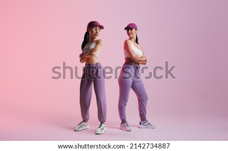 Happy young woman standing next to her metaverse avatar in a studio. Cheerful young woman smiling at the 3D simulation of herself. Young woman exploring virtual reality.