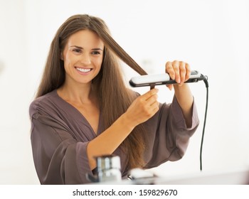 Happy Young Woman Straightening Hair With Straightener