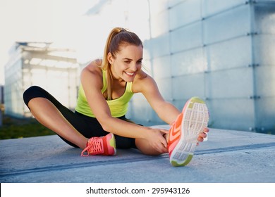 Happy young woman stretching before running outdoors - Shutterstock ID 295943126