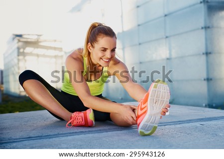 Happy young woman stretching before running outdoors