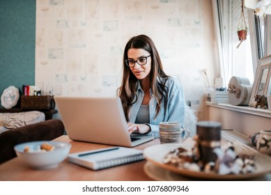 Happy Young Woman Studying On Laptop At Her Apartment.