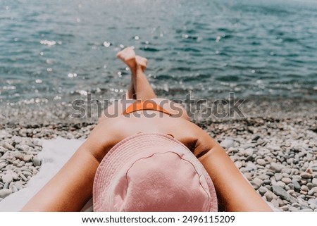 Happy young woman sunbathing or tanning on a seaside beach during summer vacation. smiling tourist in red swimsuit enjoying sun tan lying on beach near to calm clear sea water.