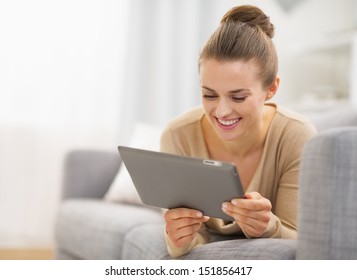 Happy Young Woman With Tablet Pc Laying On Sofa