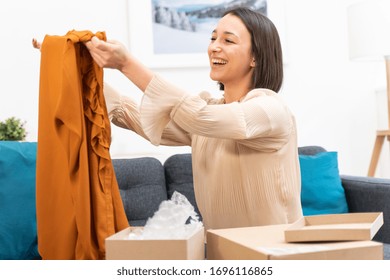 Happy Young Woman Taking Clothes Out Of Box After Delivery