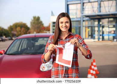 Happy Young Woman Tearing Learner Driver Sign Near Car
