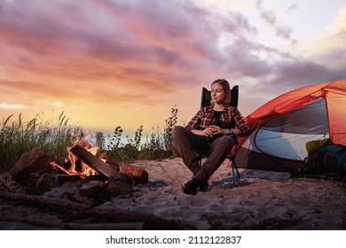 Happy young woman tourist sitting in touristic tent at evening time.