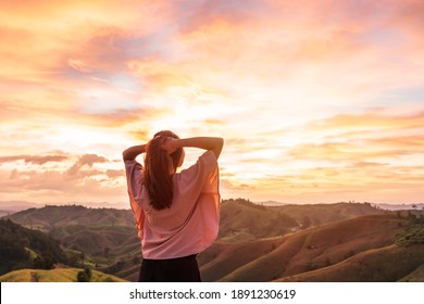 Happy young woman traveler relaxing and looking at the beautiful sunset on the top of mountain - Shutterstock ID 1891230619