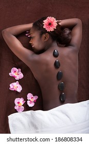 Happy young woman undergoing lastone therapy at beauty spa