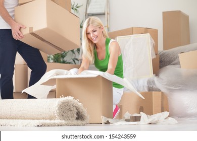 Happy Young Woman Unpacking Boxes In New Home