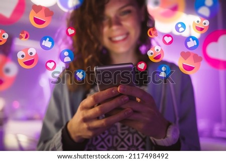 Happy young woman using her phone to interact with social media, getting followers, likes, emoji feedback