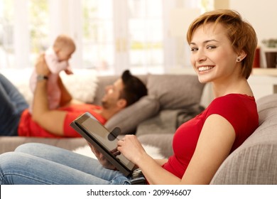 Happy Young Woman Using Tablet Pc At Home, Family Playing At Background.