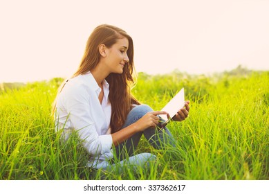 Happy Young Woman Using Tablet Outdoors 