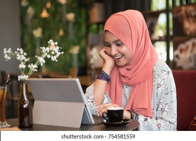 Happy young woman using tablet computer in a cafe while enjoy the coffee. - Powered by Shutterstock