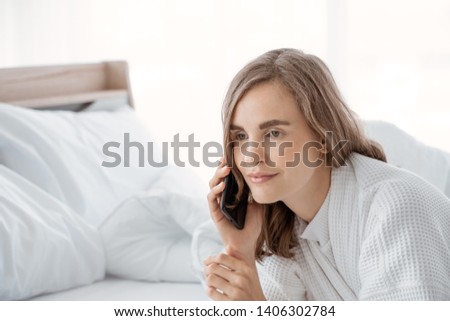 Happy young woman waiting for phone call in bed