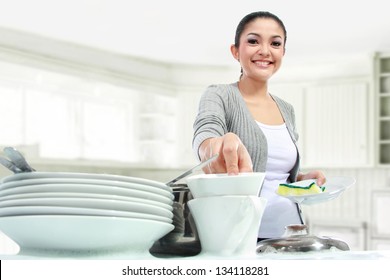Happy Young Woman Washing Dishes in the kitchen