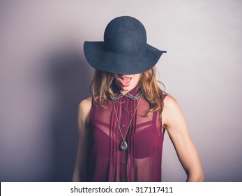 A Happy Young Woman Wearing A Hat And A See Through Shirt Is Smiling