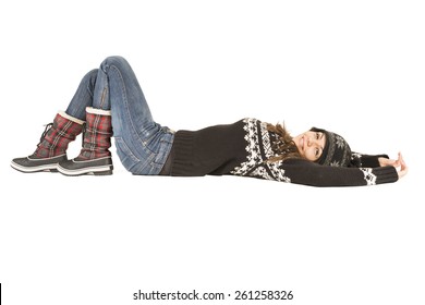 Happy Young Woman Wearing Warm Winter Clothing Laying Down On The Floor, Studio Shot On White Background